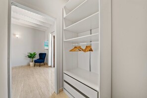 Ein begehbarer Kleiderschrank mit weißen Regalen und Holzaufhängern.