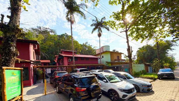 A parking area with several cars, a signboard, and a building with a red facade.