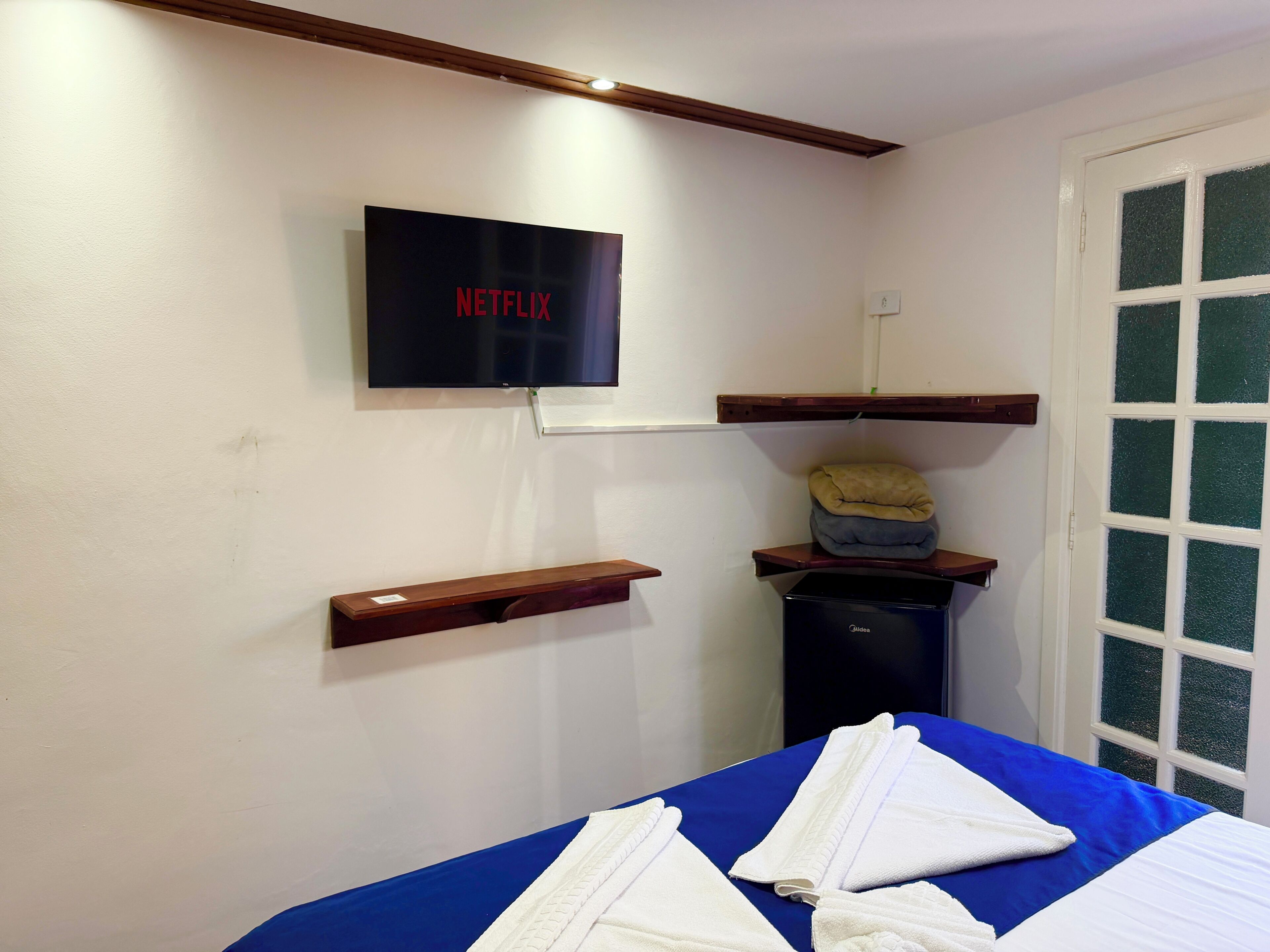 A room with a bed, a television mounted on the wall, and a window with a view.