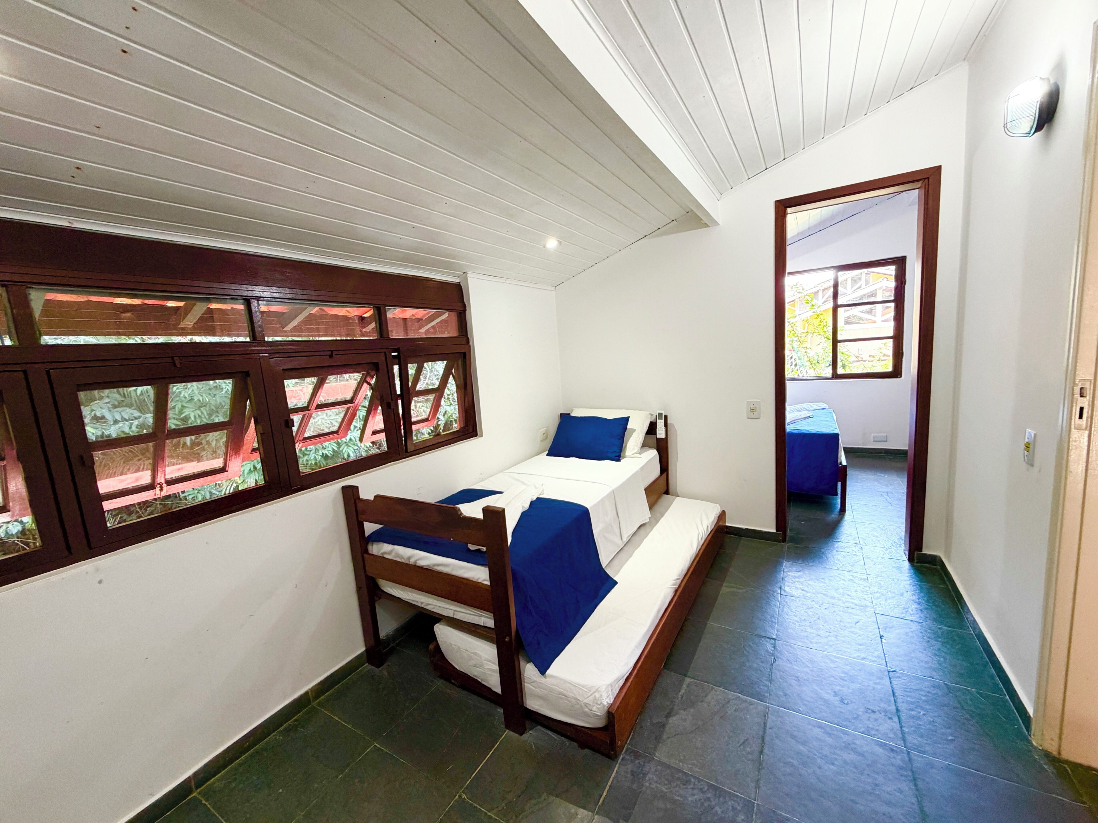 A room with a bed, a window with a view, and a door leading to another room.