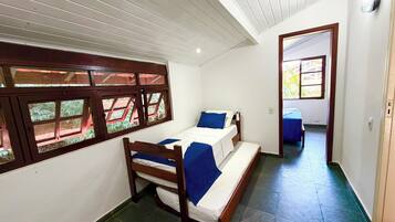 A room with a bed, a window with a view, and a door leading to another room.