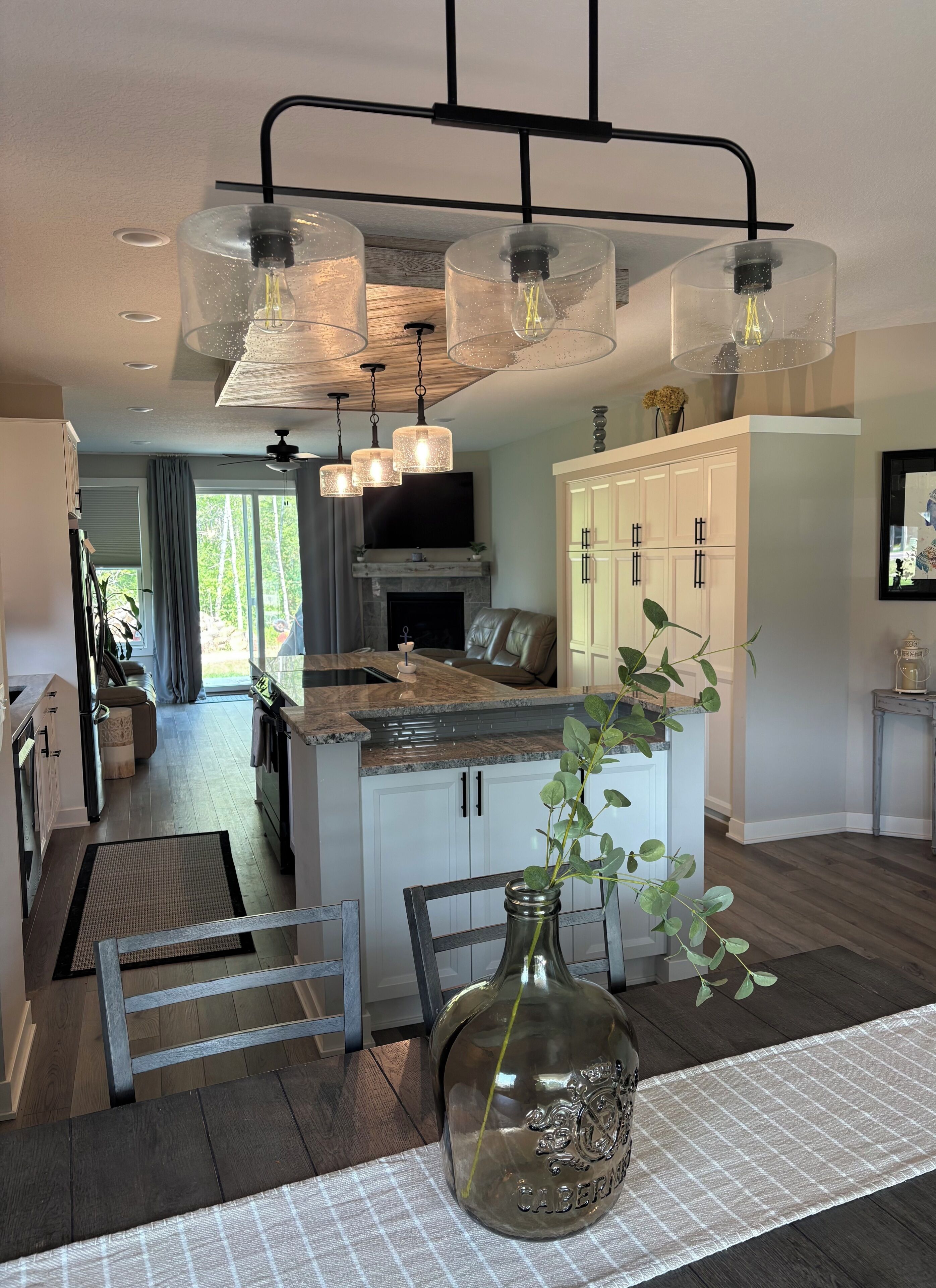 A modern kitchen with a central island, pendant lighting, and a dining area with a table and chairs.