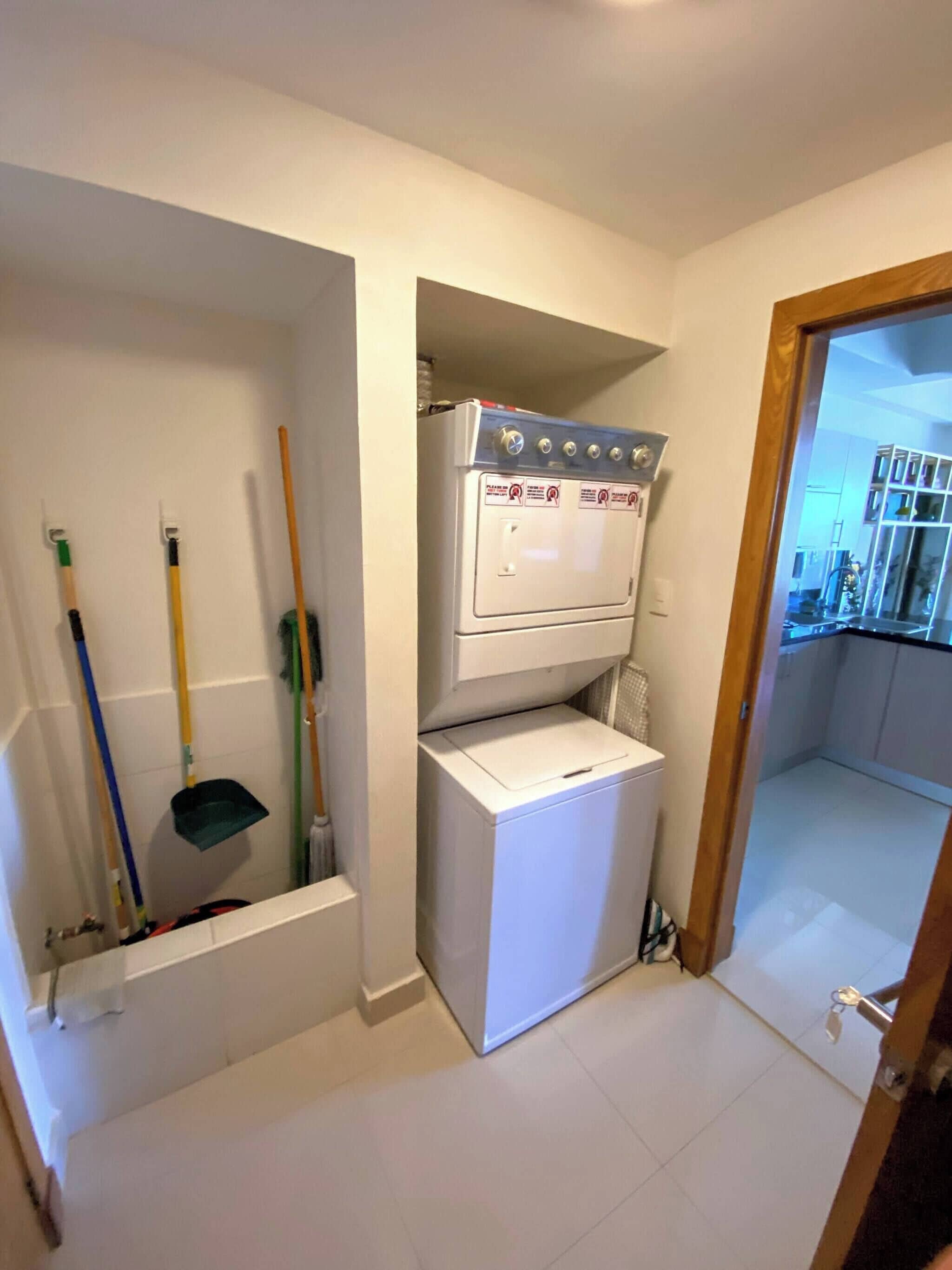 Une buanderie équipée d’un lave-linge et d’un sèche-linge, ainsi que d’un balai et d’une serpillière.