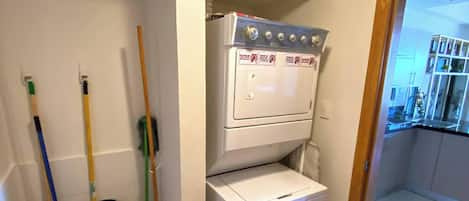Une buanderie équipée d’un lave-linge et d’un sèche-linge, ainsi que d’un balai et d’une serpillière.