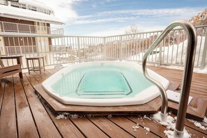 A hot tub on a wooden deck with a metal railing, surrounded by snow. - ST406 | Newly Modern| Close access + Across Street from Slopes (Steamboat Springs)