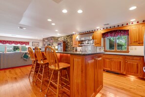 Une cuisine moderne avec des meubles en bois, un îlot central et un mur d’accent en pierre.
