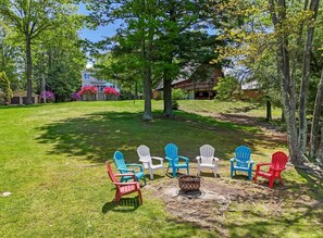 A grassy outdoor area with Adirondack chairs arranged around a fire pit. - Griffin Lakefront on Lake Wallenpaupack with Private Dock, AC - sleeps 10 (Greentown)