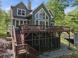 A two-story house with a wooden deck and a covered outdoor area.