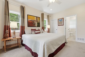 A bedroom with a large bed, a nightstand, a wooden chair, a ceiling fan, and a painting on the wall. - Lake Wallenpaupack Lakefront with private dock in Knollwood 3 Masters sleeps 10 (Lake Ariel)