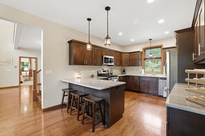 A modern kitchen with wooden cabinets, stainless steel appliances, and a central island with bar stools. - Lake Wallenpaupack Lakefront with private dock in Knollwood 3 Masters sleeps 10 (Lake Ariel)