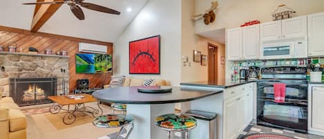 Une cuisine moderne dotée d’un îlot central, d’une cheminée en pierre et d’un ventilateur de plafond.