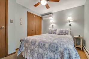 Ein Schlafzimmer mit einem Bett, zwei Wandlampen, einer Klimaanlage und einem Deckenventilator.