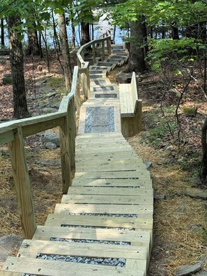 A wooden staircase leading up a hill, surrounded by trees and rocks.