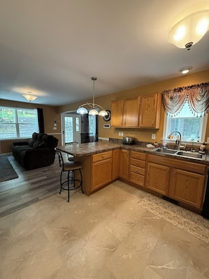 A spacious kitchen with wooden cabinets, a granite countertop, and a large island. - Rocky Road Chalet - Masthope (Lackawaxen)