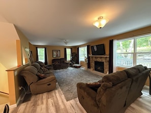 A living room with a sectional sofa, a fireplace, and large windows.