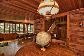 A wooden interior with a globe on a table, a staircase, and large windows. - Sunny Point Lake Wallenpaupack Lakefront with private dock - 4 bedroom sleeps 9 (Lakeville)