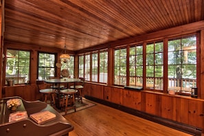 A wooden interior with a dining area, large windows, and a view of the outdoors. - Sunny Point Lake Wallenpaupack Lakefront with private dock - 4 bedroom sleeps 9 (Lakeville)