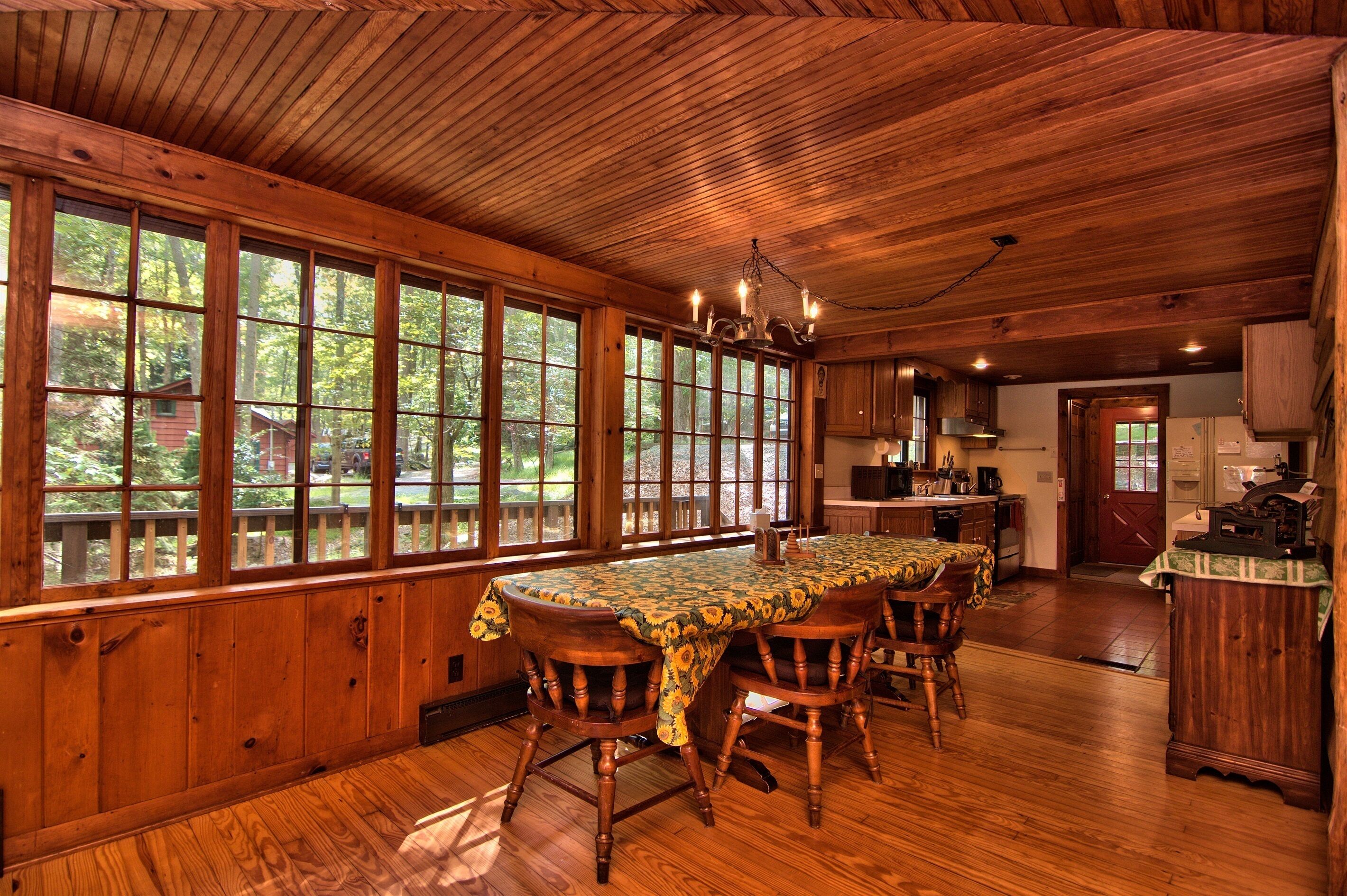 Un intérieur en bois avec une grande table à manger, des chaises et un coin cuisine.