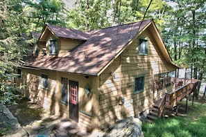 A cabin with a steeply pitched roof, a front door, and a small porch with steps leading up to it. - Sunny Point Lake Wallenpaupack Lakefront with private dock - 4 bedroom sleeps 9 (Lakeville)