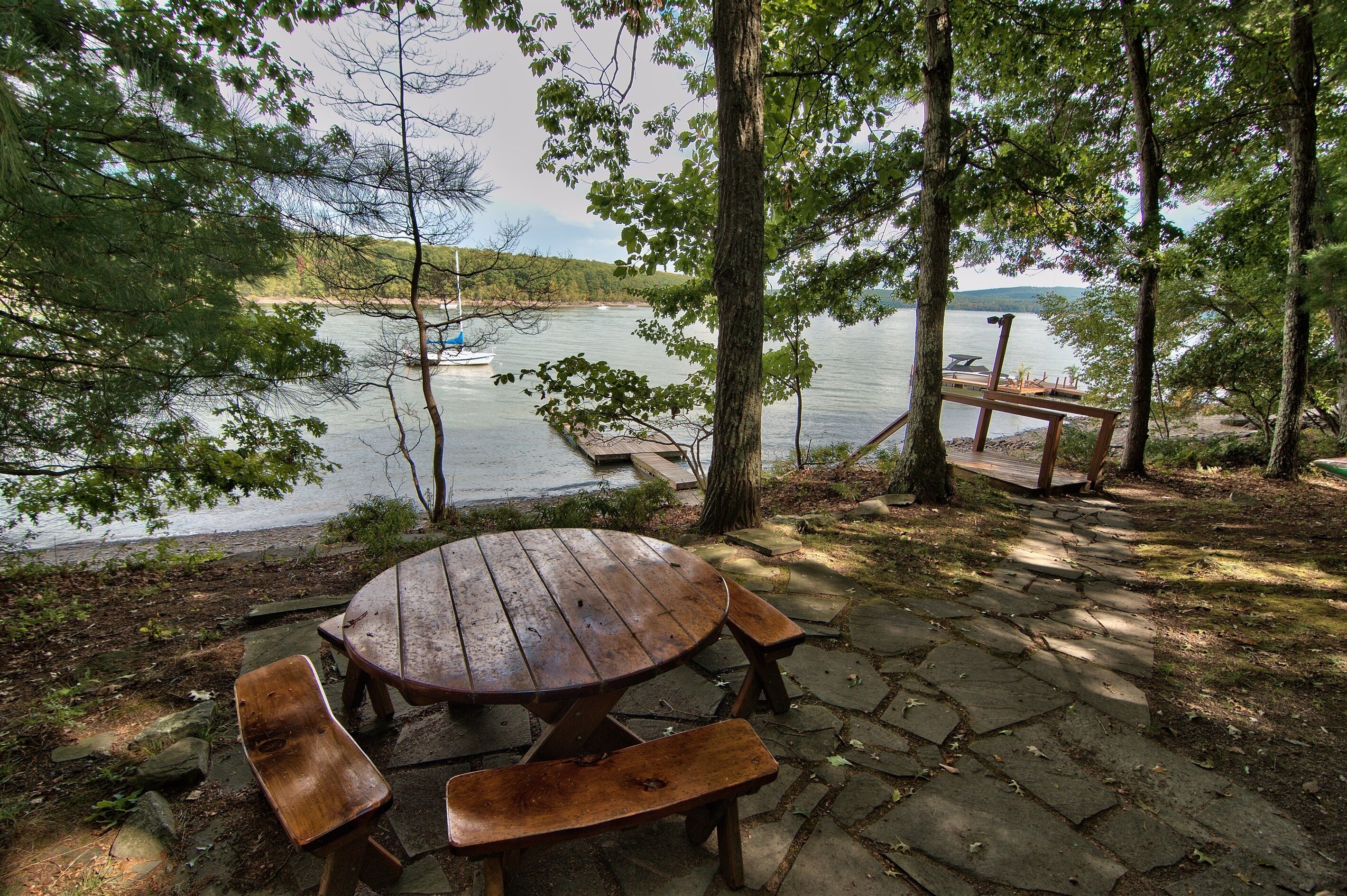 A picnic table with benches, a wooden deck, and a view of a lake.