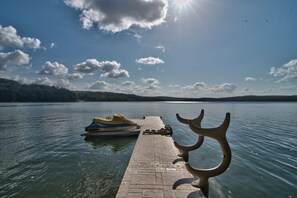 A pier extending into calm water with a boat docked at the end. - Sunnyview Wallenpaupack Lakefront Chalet Spectacular Sunsets  private dock (Paupack)
