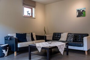 A living room with two sofas, a coffee table, and a small table with a lace tablecloth. - Accessible Stay at the Alfonsinehoeve (Heers)