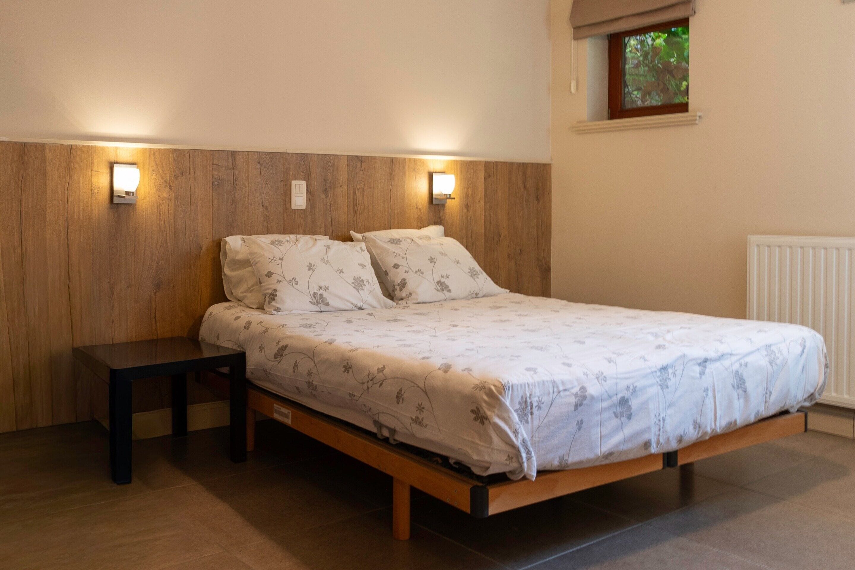 A single bed with a wooden headboard and two wall-mounted lights.