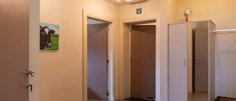 A hotel corridor with a door on the left, a mirror on the right, and a green exit sign above.