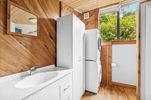 A compact, modern bathroom with a wooden interior, a white sink, and a built-in washing machine.