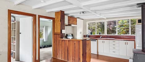 A spacious kitchen with wooden cabinetry, a built-in island, and a large window overlooking greenery.