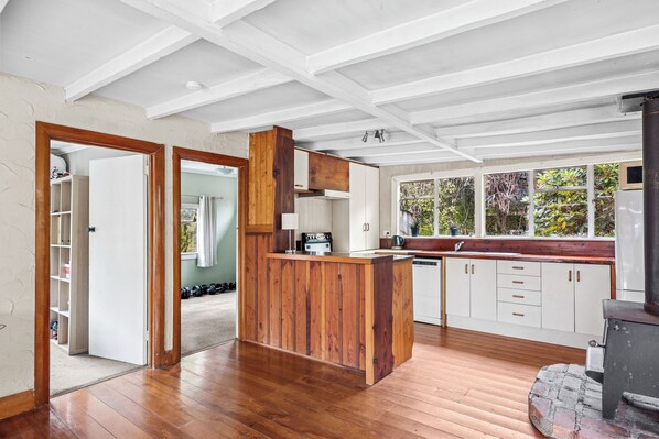 A spacious kitchen with wooden cabinetry, a built-in island, and a large window overlooking greenery.