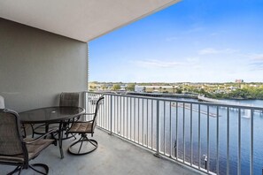 A balcony with a round table and chairs, overlooking a body of water and a distant cityscape. - Laketown Wharf 316 (Panama City Beach)