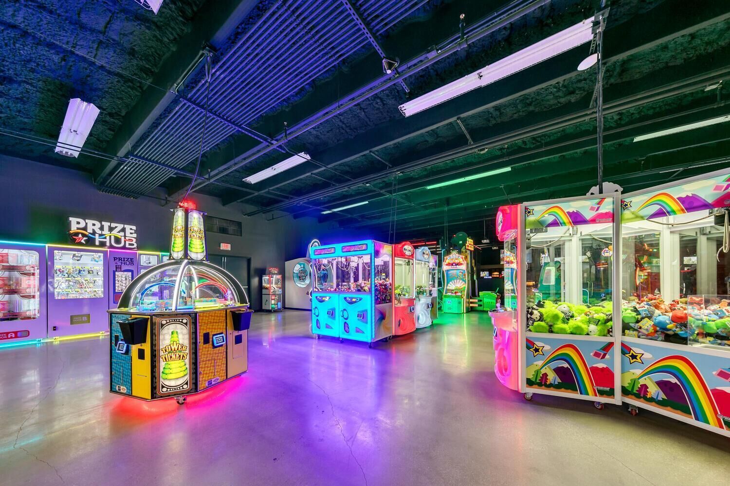 Een helder verlichte speelhal met verschillende grijpmachines en een prijszone.
