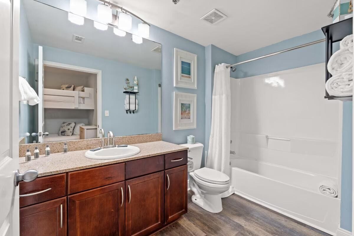 Une salle de bain comprenant un meuble-lavabo, un lavabo, un miroir, des toilettes et un espace douche.