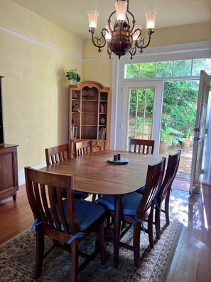 A dining room with a large wooden table, six chairs, a chandelier, and a bookshelf. - Charming 4-Bed Sausalito Home with Bay Views & Garden Patio near San Francisco (Sausalito)