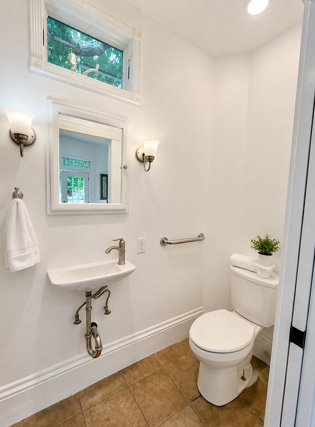 Een badkamer met toilet, wastafel en een raam boven de spiegel.