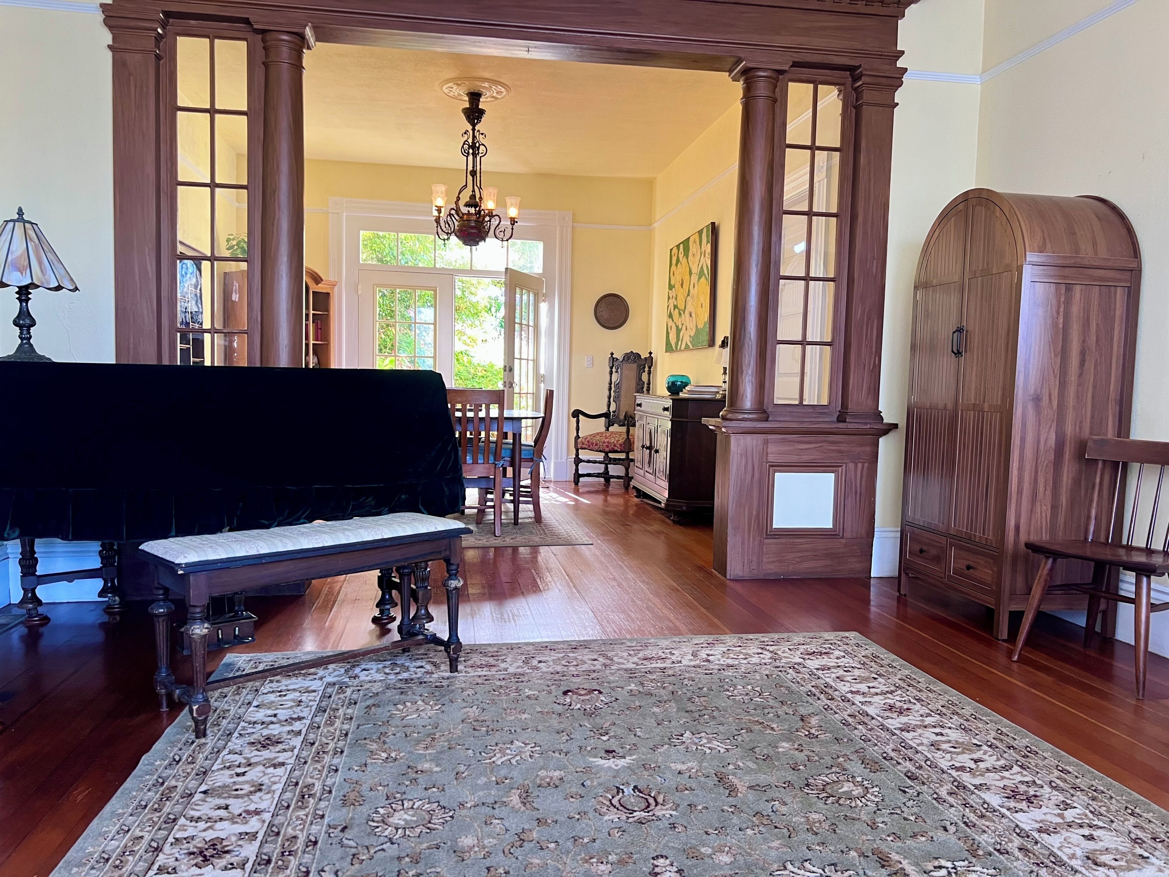 A room with a grand piano, a wooden cabinet, and a large rug.