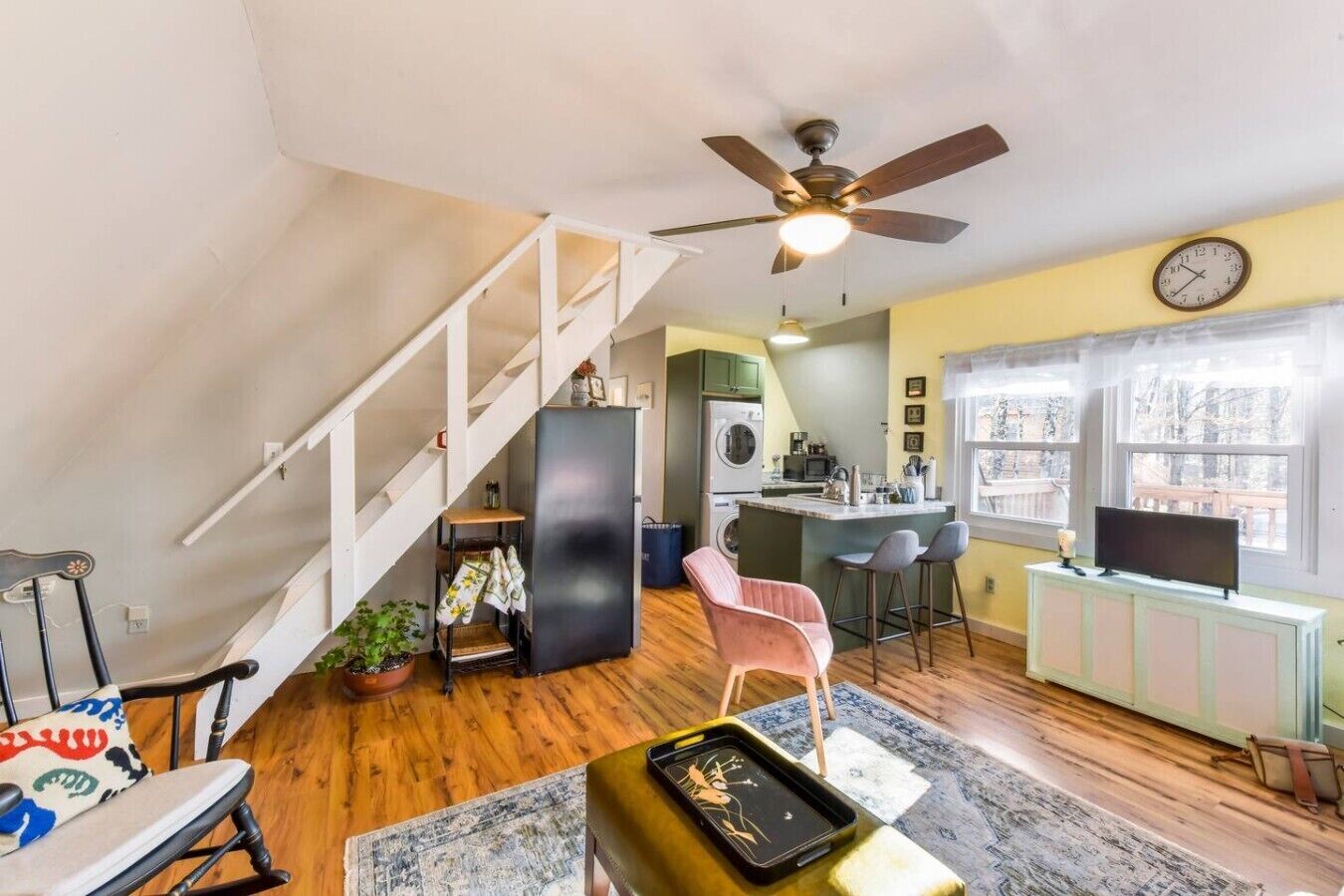 A compact living space with a kitchen, dining area, and a staircase leading to an upper level.