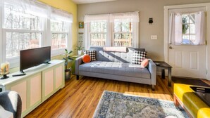 A living room with a sofa, a television, a small table, and a door.