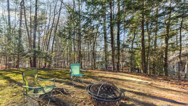 A campsite with two green camping chairs and a metal fire pit.