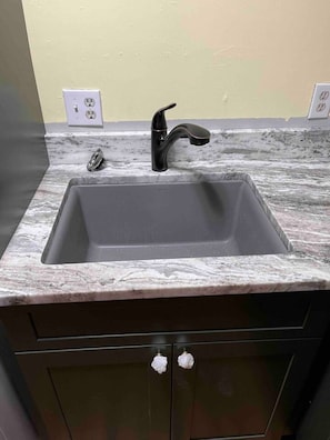 A kitchen with a dark brown cabinet, a black faucet, and a marble countertop.