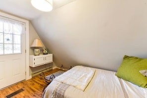 A bedroom with a bed, a nightstand, a lamp, a window with curtains, and a star decoration.