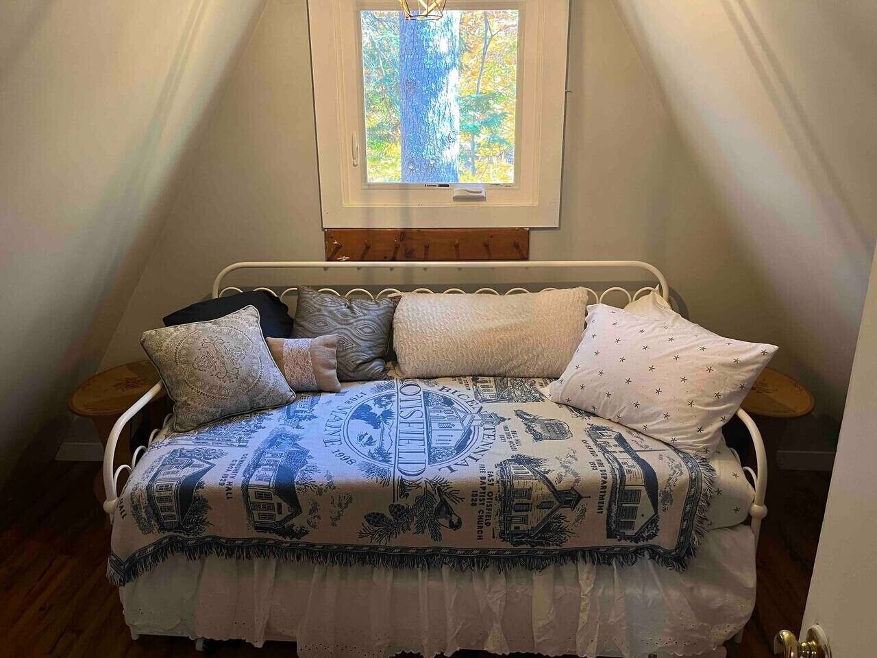 A bed with a patterned bedspread, two pillows, and a window above.