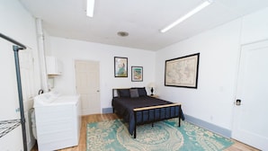 Un dormitorio con cama, cómoda, alfombra y un panel de pared con cuadros.