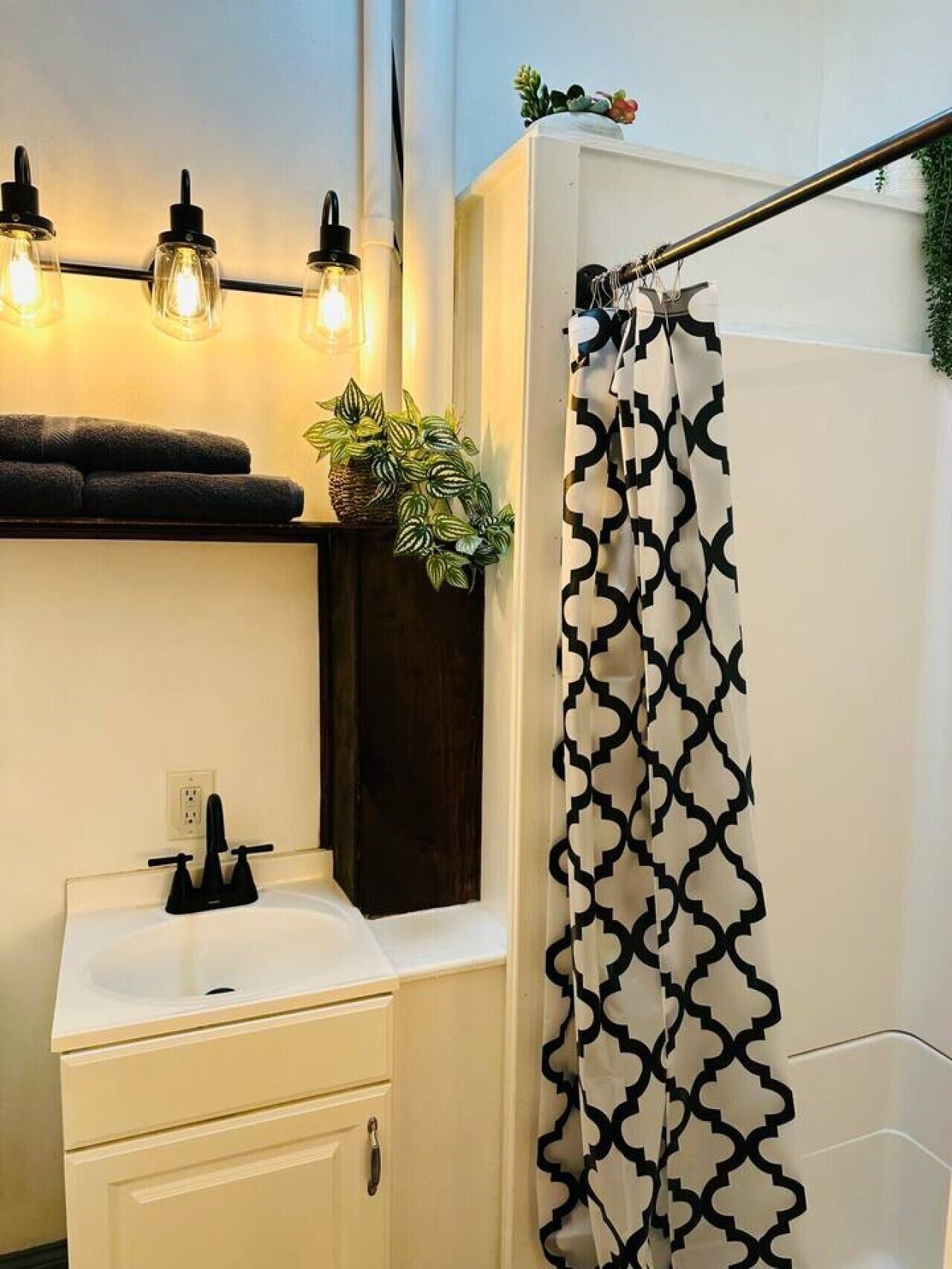 Un baño con lavamanos blanco, toalla negra y cortina de ducha estampada.