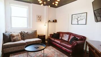 A living room with a brown sofa, a red leather couch, a coffee table, and a patterned rug.