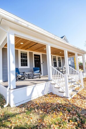 A two-story house with a covered porch, a front door, and a staircase leading to the upper floor.