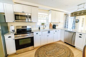 A kitchen with white cabinets, a stainless steel oven, a microwave, and a dishwasher.