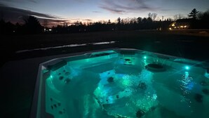 A hot tub with a view of a sunset and a house in the background.