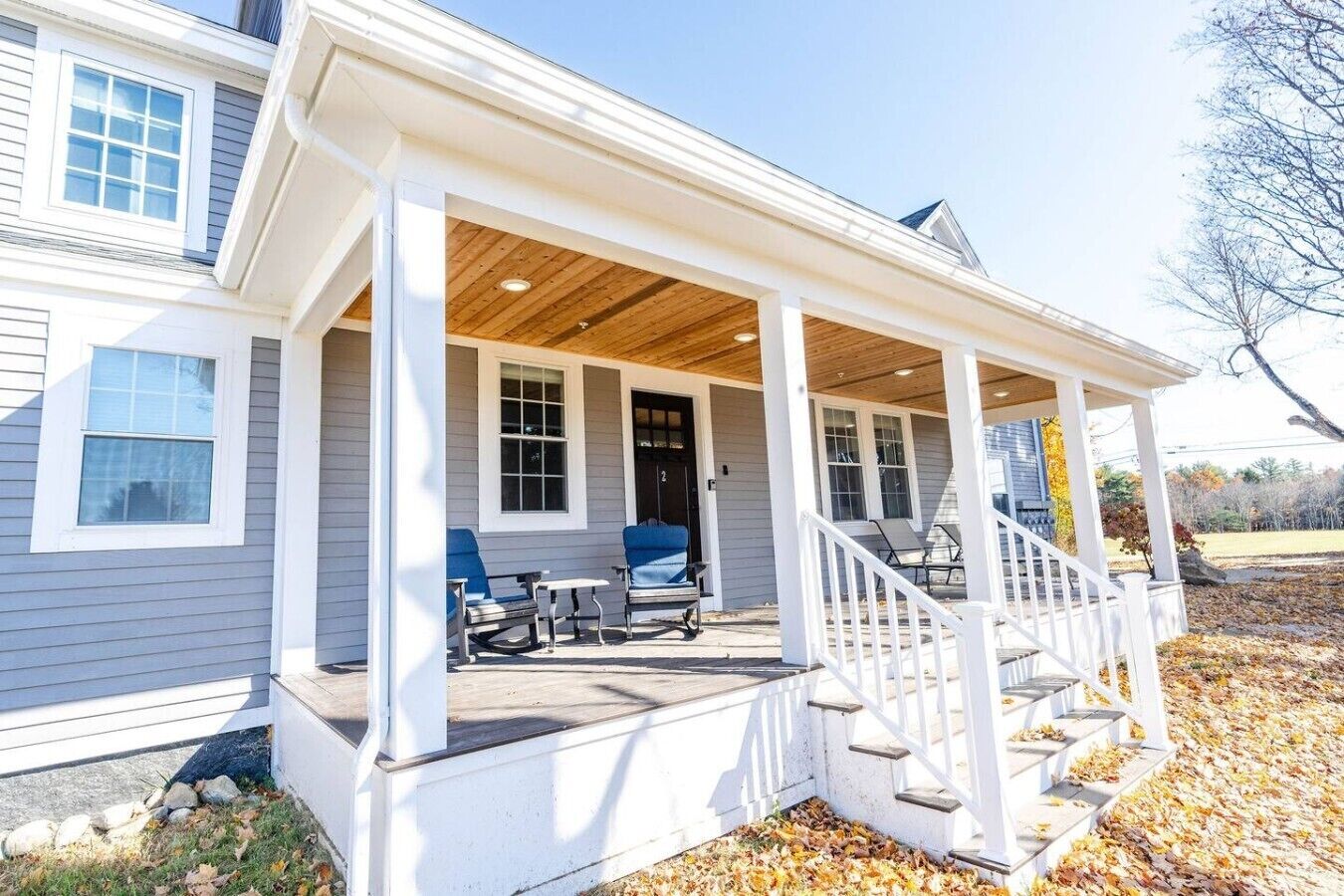 A house with a covered porch, a staircase, and two chairs.
